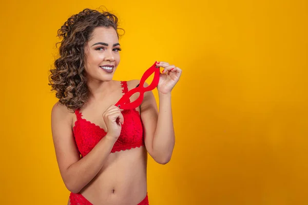 beautiful woman in sexy red lingerie holding fancy mask in her hand.