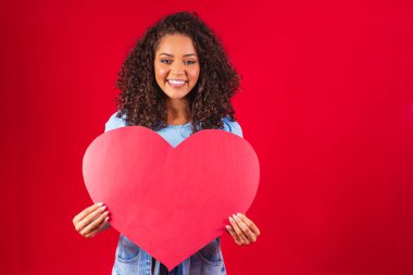 El ele tutuşan afro kız. Kırmızı arka planda izole edilmiş kalp şeklinde amour.