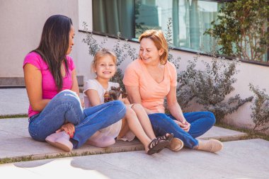 Çocuğu ve evcil köpeği olan gülümseyen lezbiyen çift. Lezbiyen çift evlatlık kızlarıyla birlikte, evlat edinme kavramı..