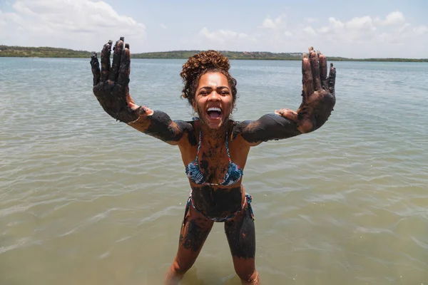 stock image Young afro woman bathing in natural clay in the river.