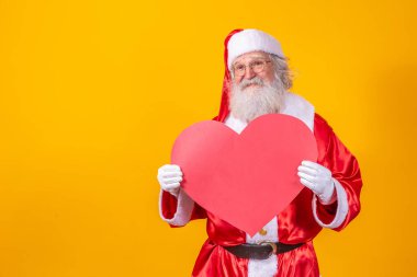 Noel Baba 'nın elinde sarı arka planda büyük kırmızı kalp kartı var. Romantik Noel Baba.