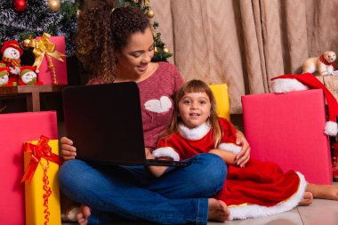 Anne ve çocuk Noel tatilinde evde dizüstü bilgisayar kullanıyor..