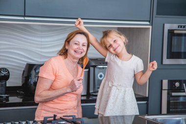 Anneler Günün kutlu olsun! Çocuk kız ve anne evde yemek pişiriyor ve eğleniyorlar. Aile tatili ve birliktelik.