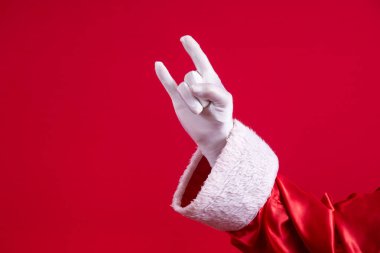 Noel Baba, elleri ve kırmızı arka planı olan rock 'n roll işareti yapıyor..