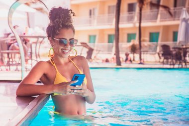 Kadın otel havuzunda cep telefonuyla çalışıyor.