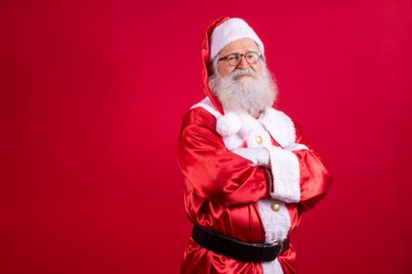 Noel Baba kırmızı arka planda kollarını kavuşturdu. Nazik sakallı Noel Baba, kolları kırmızı arka planda katlanmış. Gerçekçi Noel Baba 'nın stüdyo fotoğrafı..