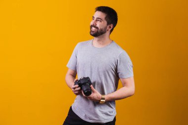 Elinde fotoğraf makinesi olan genç bir çocuk. Sarı arka planda güzel bir fotoğrafçı.
