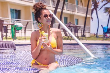 Otelde yüzme havuzunda nefis bir içki içen genç bir kadın..