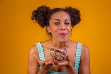 Genç afro kadın lezzetli çikolatalı çörekler yiyor..