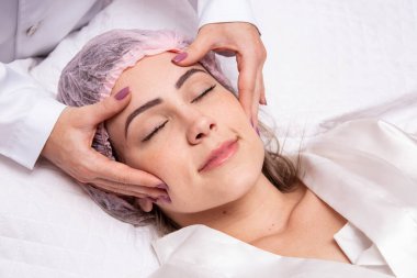 Kalın kaşlı genç bir kadın, temiz arka planda mükemmel bir ten, fotoğraf konsepti güzellik, cilt bakımı, kaplıca, tedavi, yüz masajı..