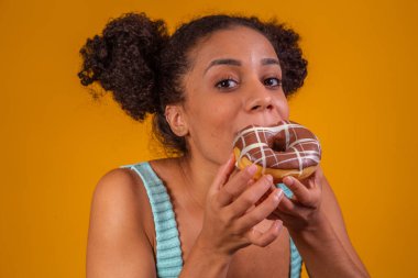 Genç afro kadın lezzetli çikolatalı çörekler yiyor..