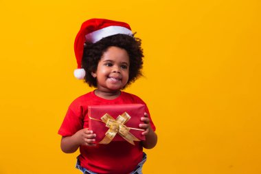 Noel Baba 'daki gülümseyen afro çocuk elinde Noel hediyesi tutan kırmızı şapka. Noel konsepti.