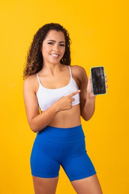 Spor uygulaması. Akıllı telefonu tutan ve gösteren heyecanlı genç adamın portresi, mesaj için boş bir ekranı işaret ediyor. Dikey
