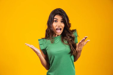 Sarı arka planda izole edilmiş heyecanlı genç bir kadın görüntüsü. Kamera görünümlü.