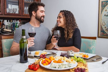 Romantik bir akşam yemeğinde şarap ve peynir tatan bir çift. Kışın şarap ve peynirli atıştırmalıklar