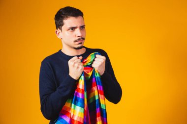 Gay gururu. Sarı arka planda lgbt bayrağı tutan eşcinsel çocuk..