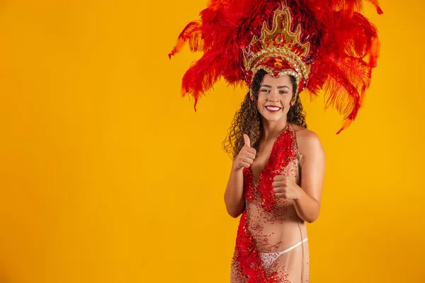 stock image Beautiful dancer is standing with her thumb up making ok or positive sign. She is wearing a red feather costume. Carnival Fantasy