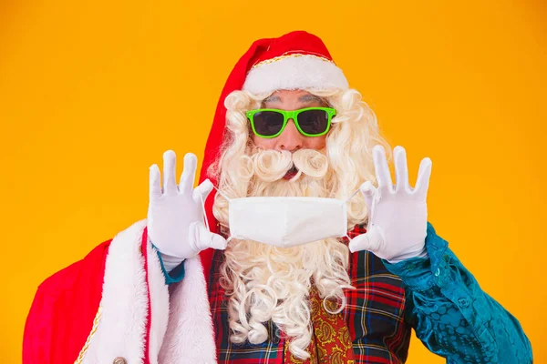 真正的黄色背景的圣诞老人手拿着保护面罩 以抵御海盗的袭击 有社交距离的圣诞节 Covid — 图库照片