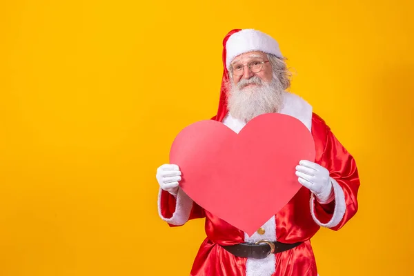 Święty Mikołaj Trzyma Dużą Czerwoną Kartę Serca Żółtym Tle Romantyczny — Zdjęcie stockowe