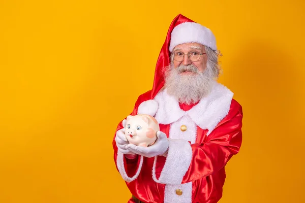 圣诞老人把硬币放进陶瓷储蓄罐里 年底的储蓄概念 花了整个圣诞节 在圣诞礼物上度过 — 图库照片