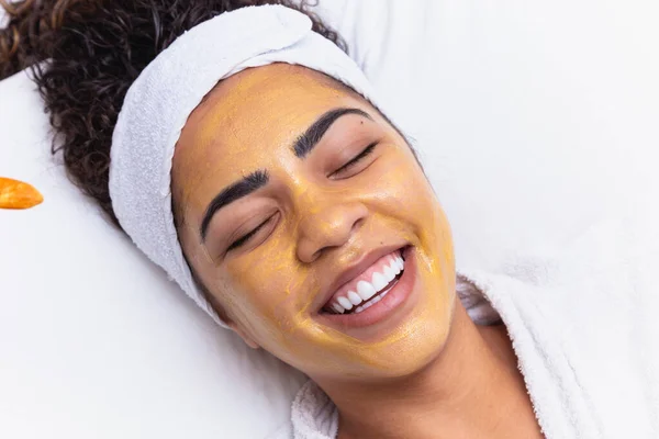 女性は顔を保湿するため美容室に寝そべってる 美容師は 患者の顔に保湿マスクを適用します — ストック写真