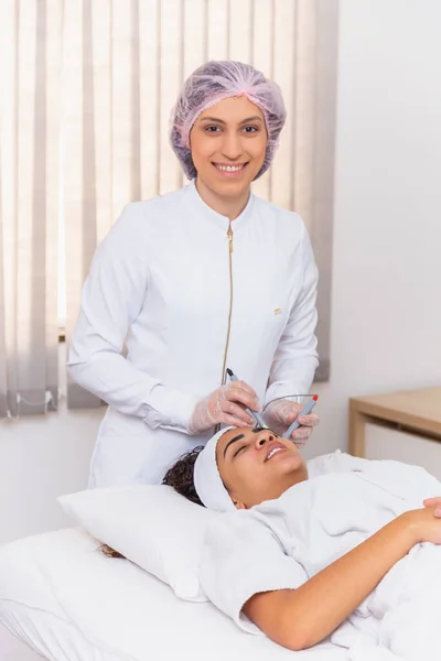 Jonge Vrouw Liggend Tafel Van Cosmetoloog Tijdens Verjongingsprocedure Cosmetoloog Verzorgen — Stockfoto