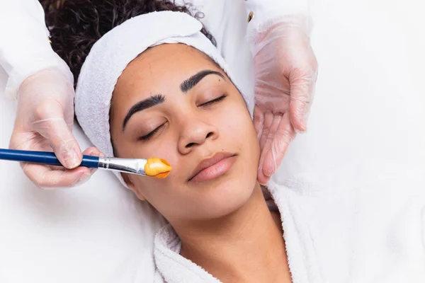 女人躺在美容师的办公室里进行脸部保湿 美容师在病人的脸上涂上保湿面膜 — 图库照片
