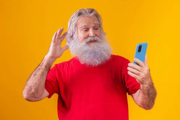 stock image Cheerful elderly man holding a smartphone, having video call online, chatting with grown children, communicating with a friend at a distance, older generation modern technology comfortable user-friendly concept.