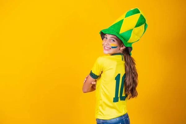 ブラジルのシャツを着て黄色の背景をした小さなブラジル人のファンの女の子 — ストック写真