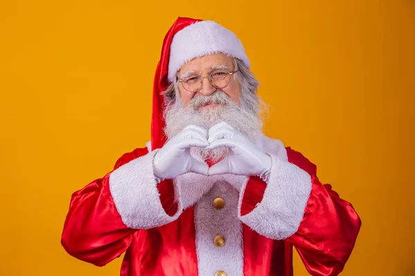 Jultomten Gör Hjärttecken Med Händerna Och Gul Bakgrund — Stockfoto