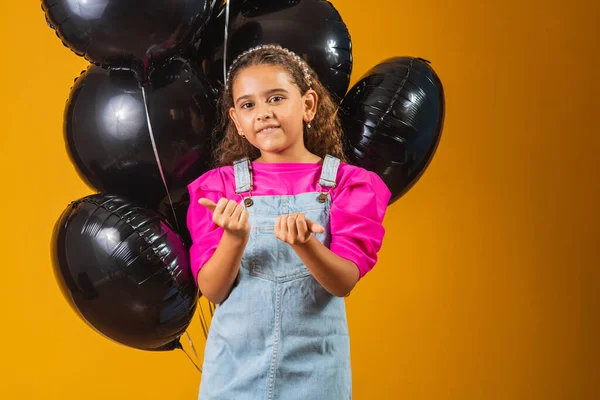 smiling little girl with black balloons on black friday. low price festival
