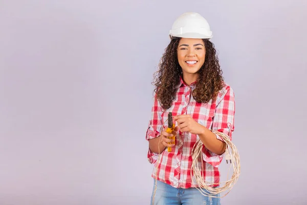 Female technique. Electrician woman on white background with space for text. Woman electrician holding wire and pliers.