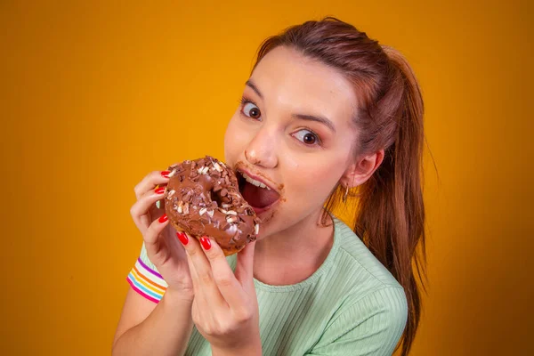 红头发的年轻女人吃着美味的巧克力甜甜圈 嘴上沾满了糖衣 — 图库照片