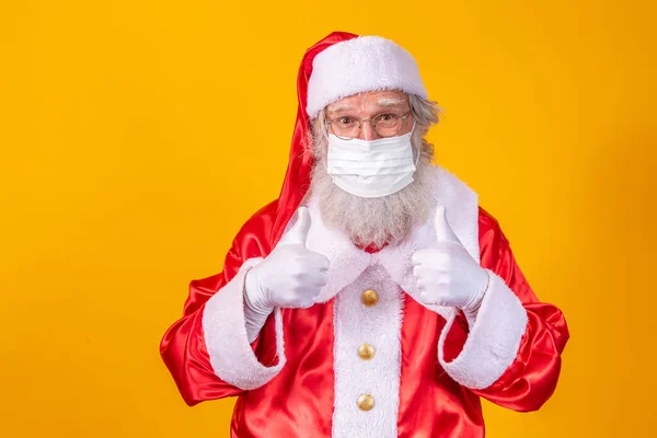 真正的圣诞老人 背景是黄色的 戴着保护面具 戴着眼镜和帽子 有社交距离的圣诞节 Covid — 图库照片