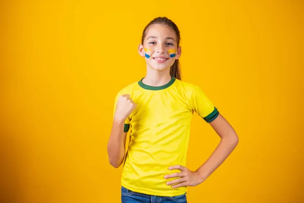 漂亮的小女孩在黄色的背景上为她的球队加油 小女孩庆祝这一目标 庆祝巴西的胜利 — 图库照片