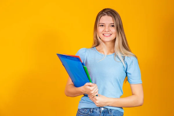 Young student girl with books on yellow background. Back to school.