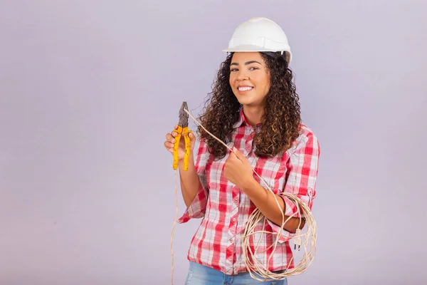 Female technique. Electrician woman on white background with space for text. Woman electrician holding wire and pliers.