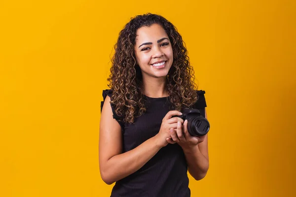 若いアフロ女性の写真黄色の背景に写真カメラを保持 — ストック写真