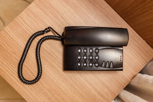 ホテルの茶色のテーブルの上に黒いヴィンテージの電話 — ストック写真