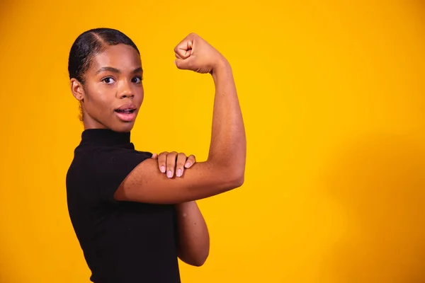 我们能做到的 女人对女性权力的拳头种族主义的女性受害者 工作中的虐待 女性的力量增强妇女权能 女人的力量 黄色背景 — 图库照片
