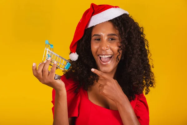 戴着圣诞礼帽的女人在买圣诞礼物 她正在展示一辆迷你推车 — 图库照片