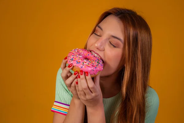 吃黄色背景粉红甜甜圈的女孩 — 图库照片