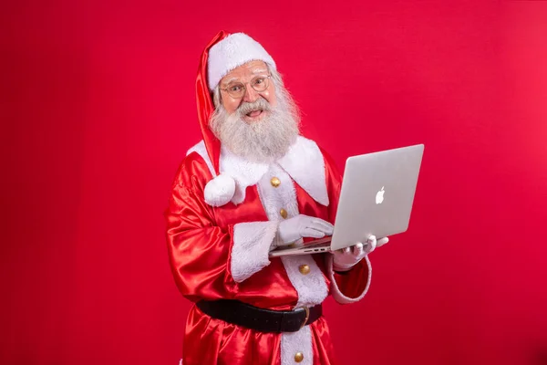 Santa Claus Pomocą Laptopa Czerwonym Tle — Zdjęcie stockowe