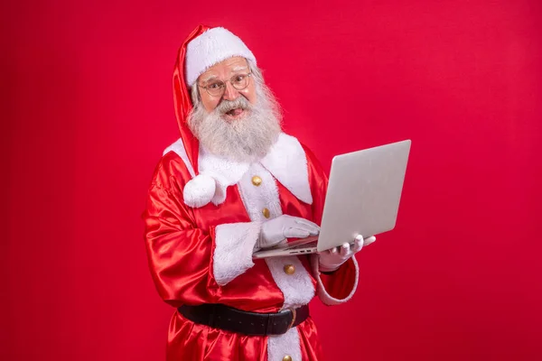Santa Claus Pomocą Laptopa Czerwonym Tle — Zdjęcie stockowe