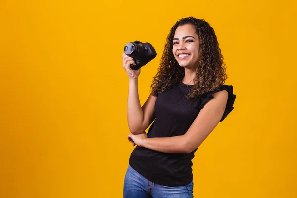 若いアフロ女性の写真黄色の背景に写真カメラを保持 — ストック写真
