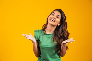 Sarı arka planda izole edilmiş heyecanlı genç bir kadın görüntüsü. Kamera görünümlü.