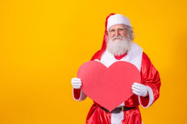Noel Baba 'nın elinde sarı arka planda büyük kırmızı kalp kartı var. Romantik Noel Baba.