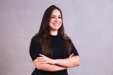 Kollarını kavuşturup kameraya bakan güzel, iri yarı bir kadın.