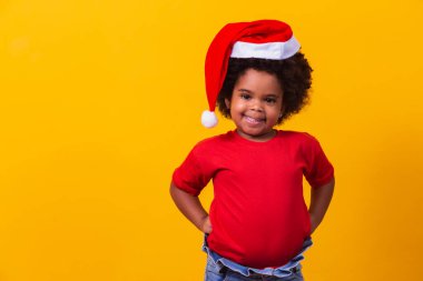 Kırmızı tişörtlü ve Noel Baba şapkalı küçük afro kız. Noel ve Yeni Yıl kampanyası