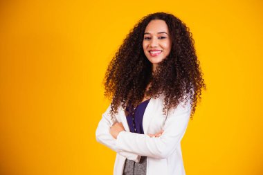 Kollarını kavuşturup kameraya gülümseyen genç afro iş kadını..